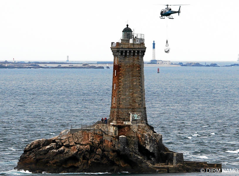 L'hélicoptère transportant des matériaux en phase d'approche du phare de la Vieille